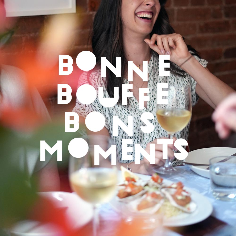 Jeune femme riant avec verre de vin blanc et table avec huîtres dans le Vieux Montréal avec le titre BONNE BOUFFE BONS MOMENTS